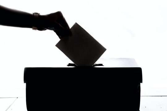 Ruka stavlja glasački papir u kutiju